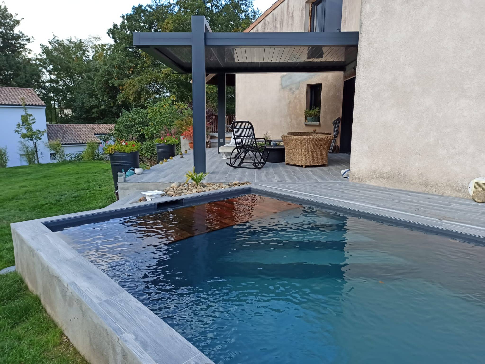 Photo d'une pergola en fer noir au bord d'une piscine en béton brut.