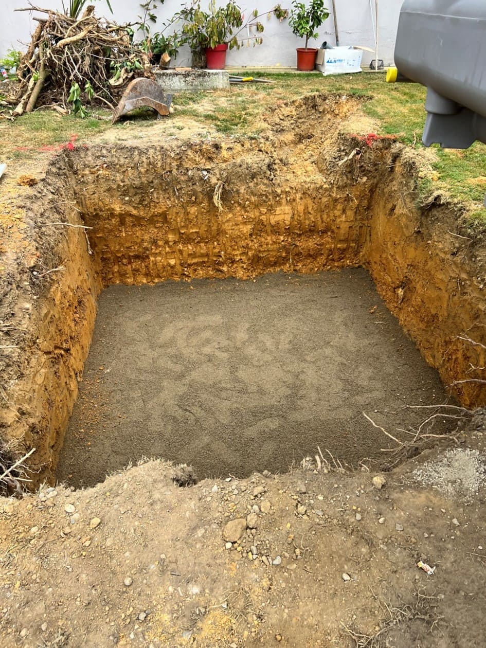 Photo d'un chantier dans un jardin, un trou d'environ deux mètres sur quatre a été creusé pour y déposer une fosse septique.